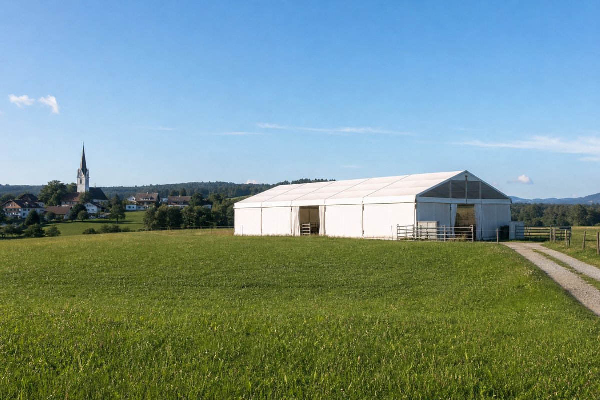 Ländliche österreichische Landschaft mit Weidezelt und Dorfkirche im Hintergrund